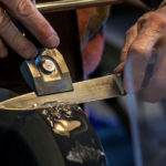 Photo of a knive being sharpened. We can only see the hands of the person, and part of the sharpening object.