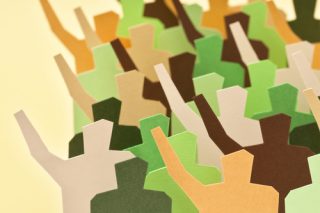 Cardboard cutouts of human figures in shades of green and brown, many with one arm raised.