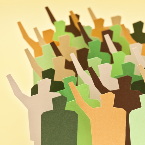 Cardboard cutouts of human figures in shades of green and brown, many with one arm raised.
