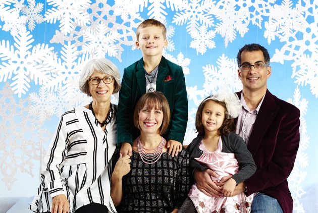 A family of five in front of a holiday backdrop.