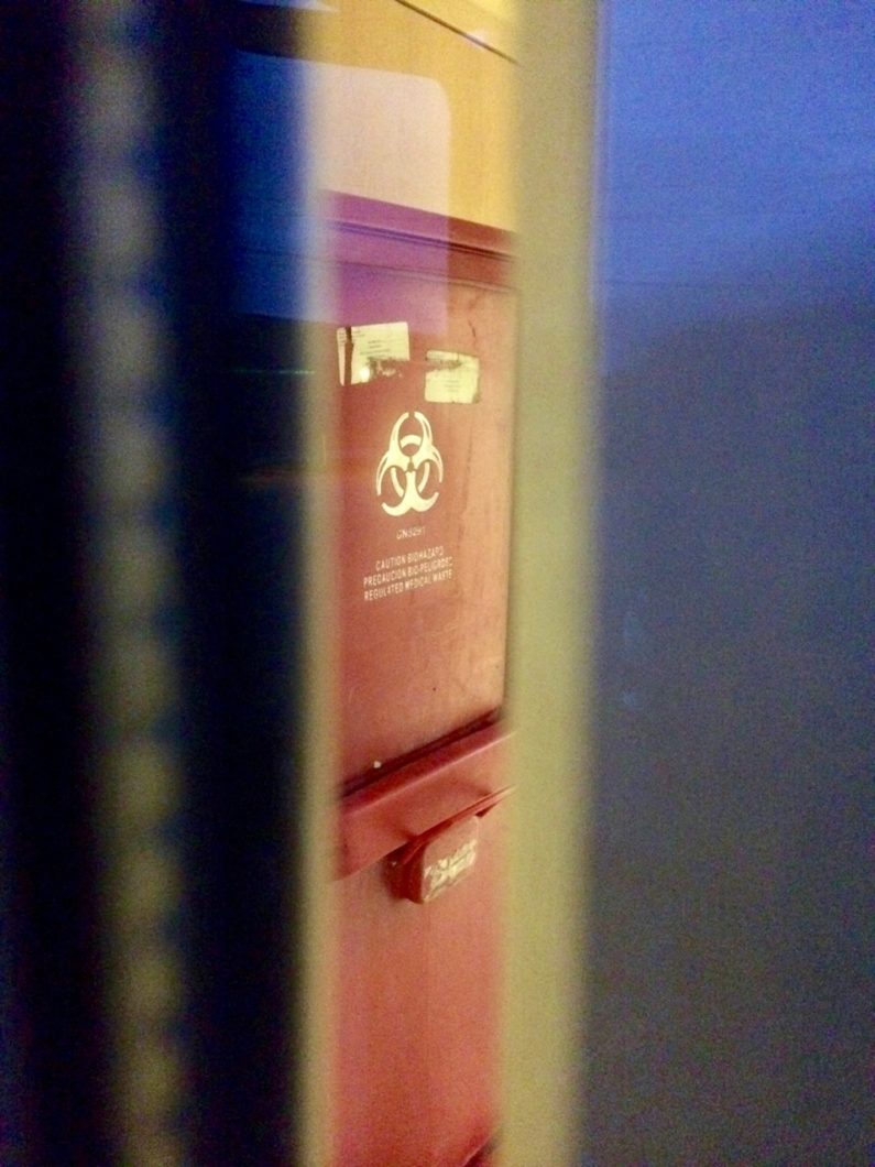 Close-up view of a red sharps receptacle.