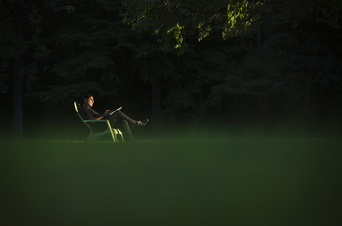 A distant shot of a man seated in a lawn chair in the dark.