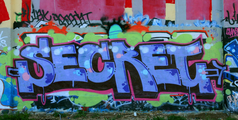 Colorful graffiti of the word secret in large purple letters on a lime, red, and white background.
