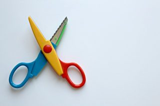 A photo of a colorful pair of scissors, on a white surface.