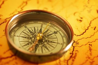 A close-up photo of a compass sitting on a map.
