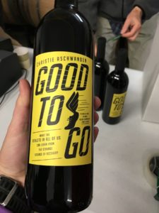 A hand holding a bottle of wine with the Good to Go label, matching the book cover.