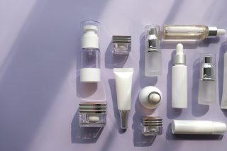 A variety of generic cosmetic containers on a purple surface.