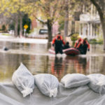 Photo of a flooded street, showing what appears to be an emergency team on a boat.
