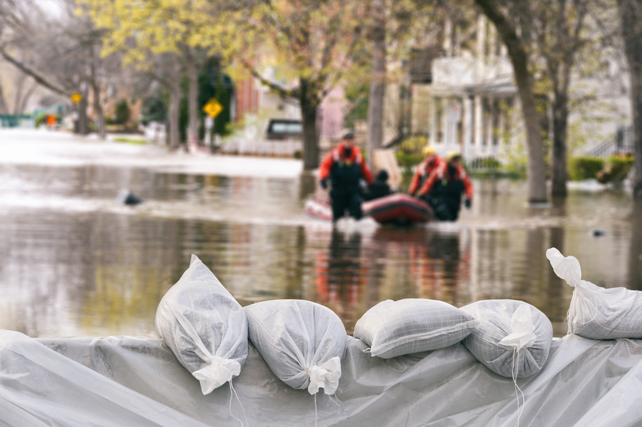 A flooded street and an emergency team on a boat filled with sandbags.