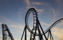 A photo of a roller coaster, with a dark blue sky and a few clouds in the background.