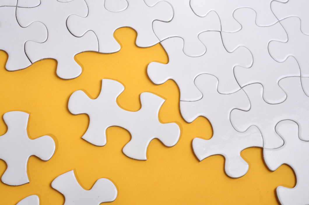A partly assembled white jigsaw puzzle on a yellow background.